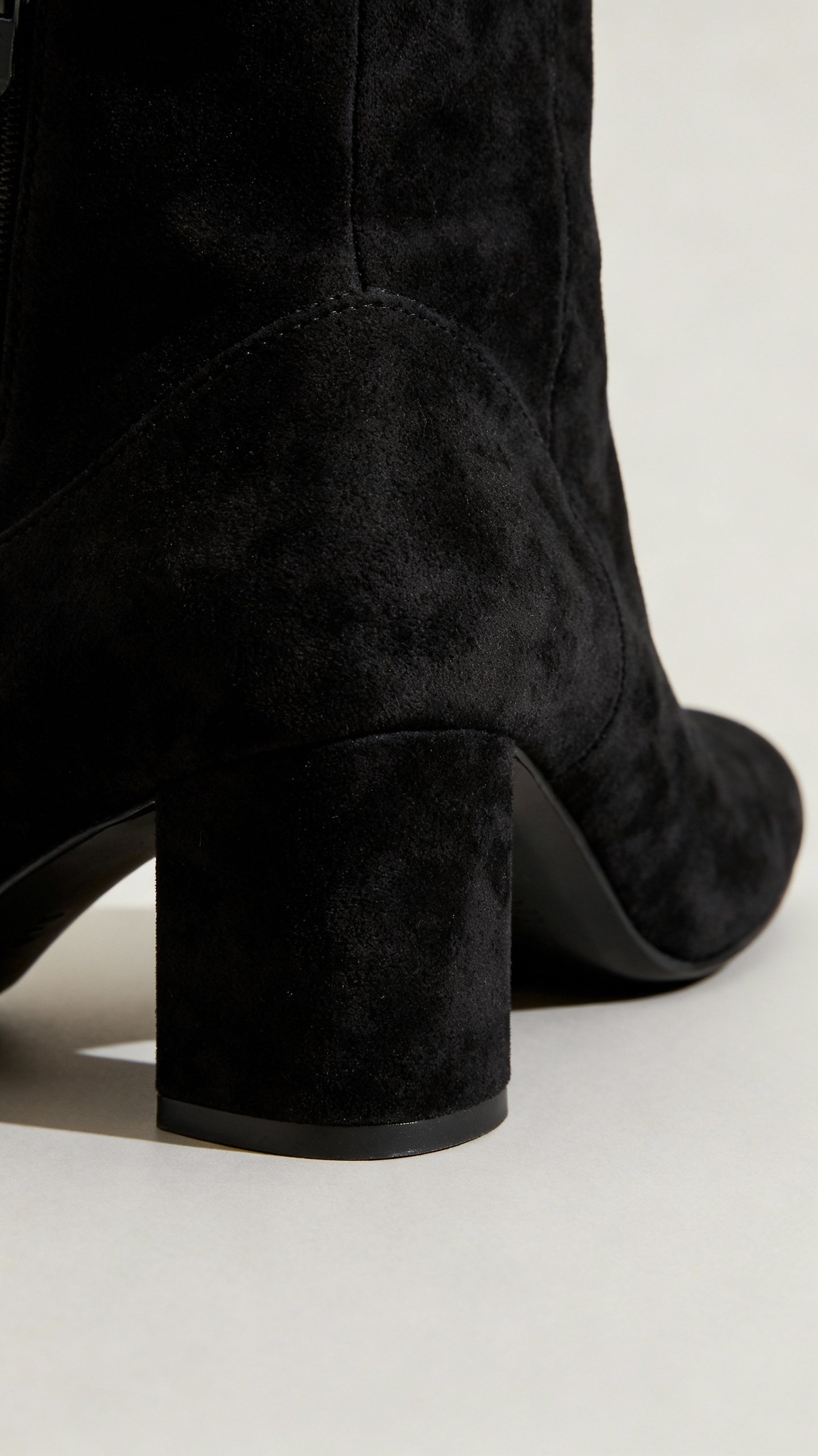 Closeup of black suede block-heel pump bending at forefoot