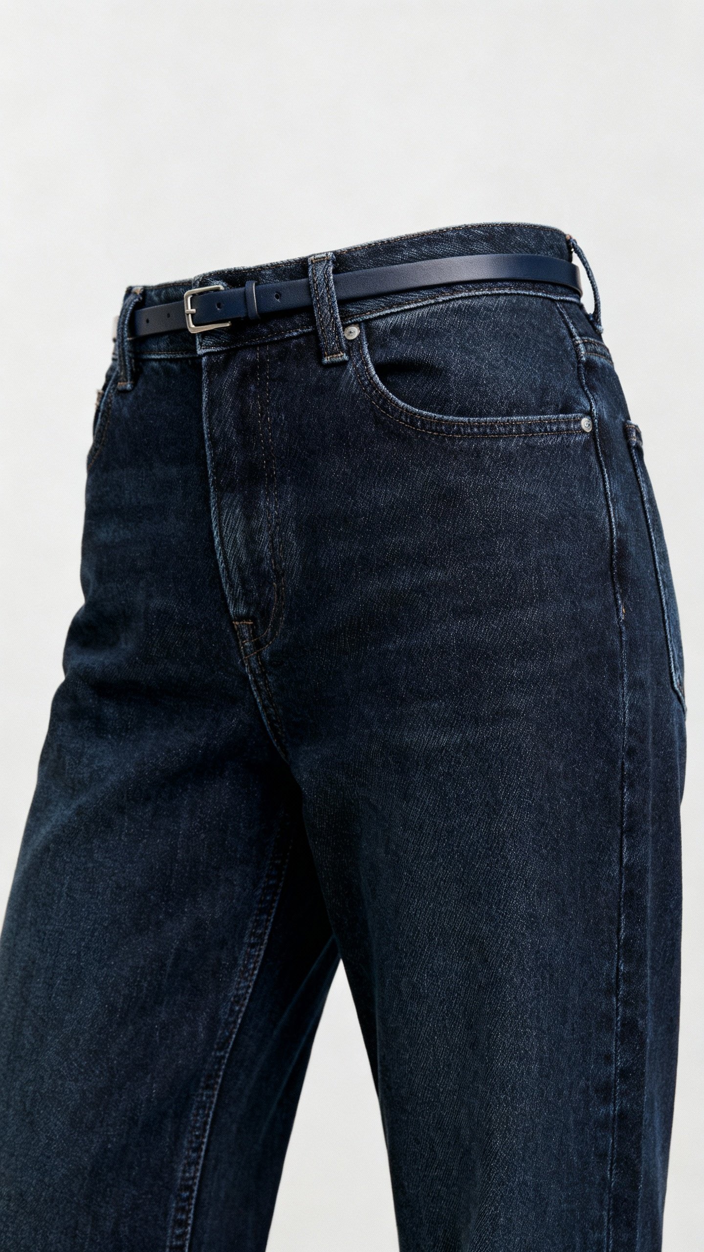 Closeup of high-rise straight jeans with skinny belt, dark wash