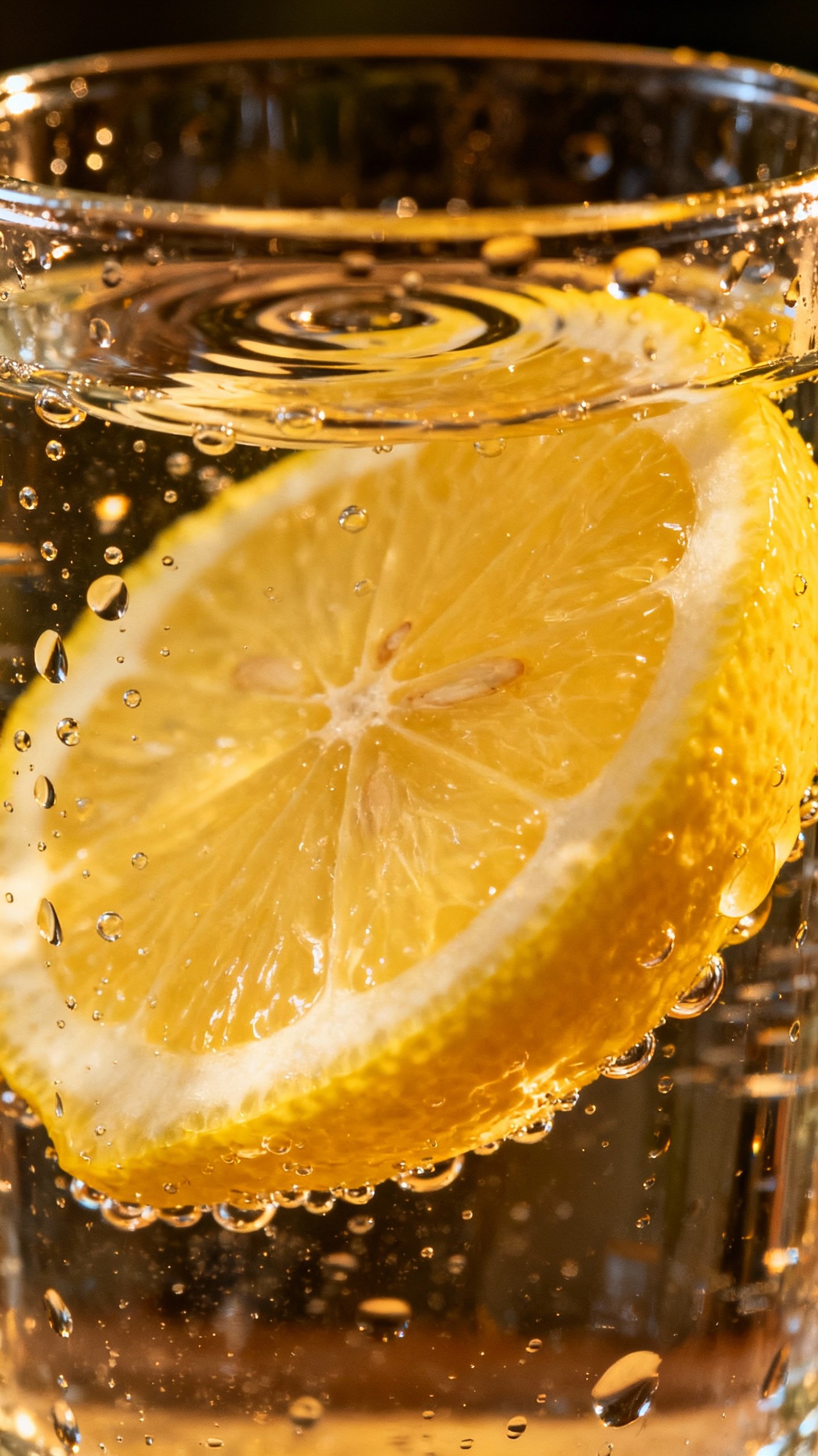 Closeup of lemon slice squeezed into water glass, condensation
