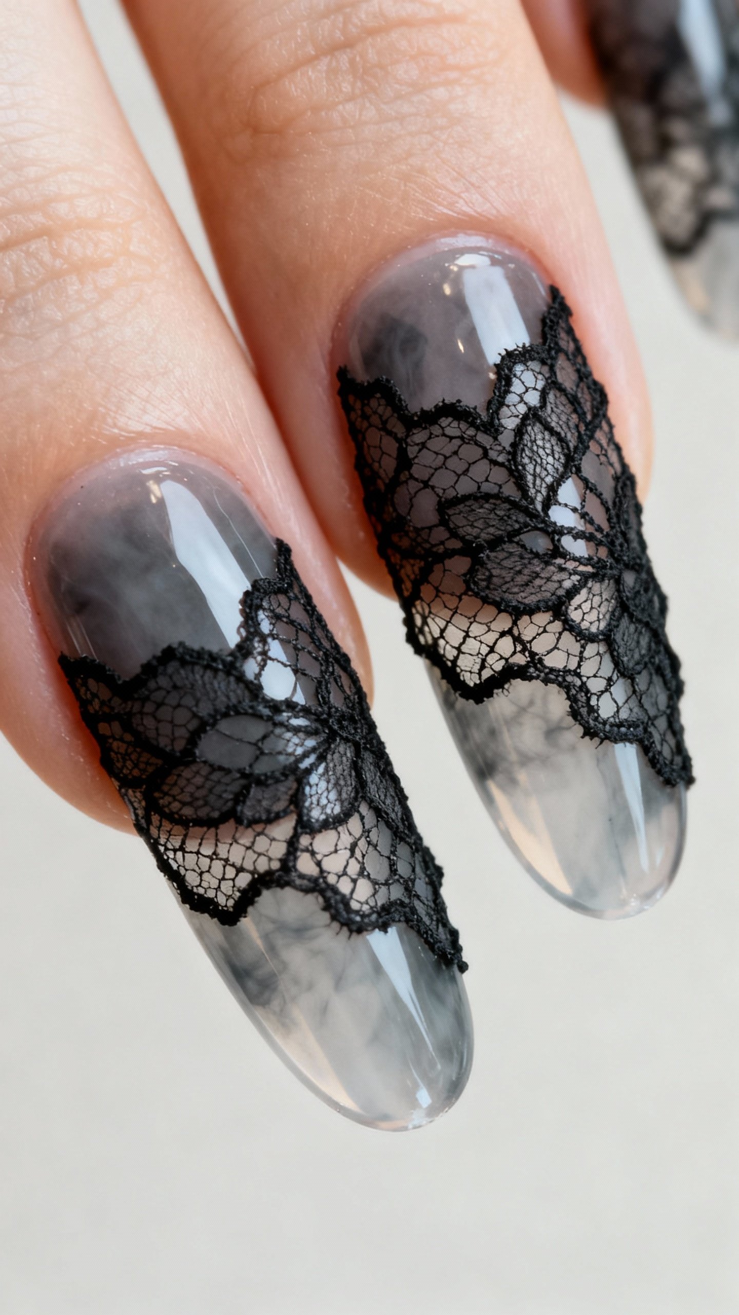 Closeup translucent smoke-grey nails with black lace veils, two feature nails