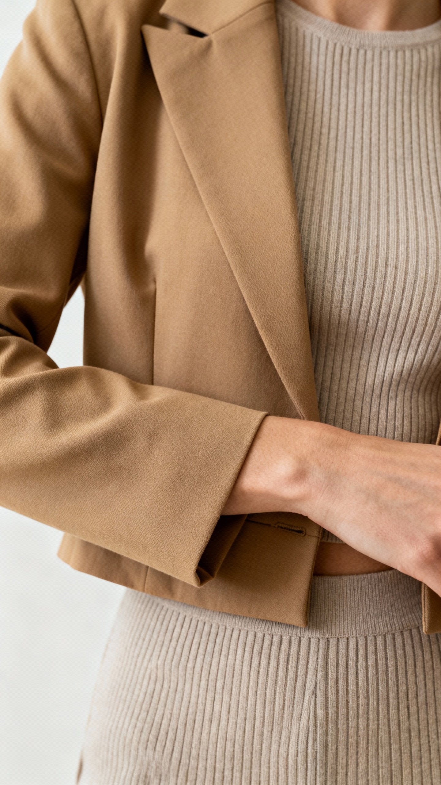 Cropped camel blazer nipped at waist over fitted knit top, closeup of sleeve hitting wrist bone