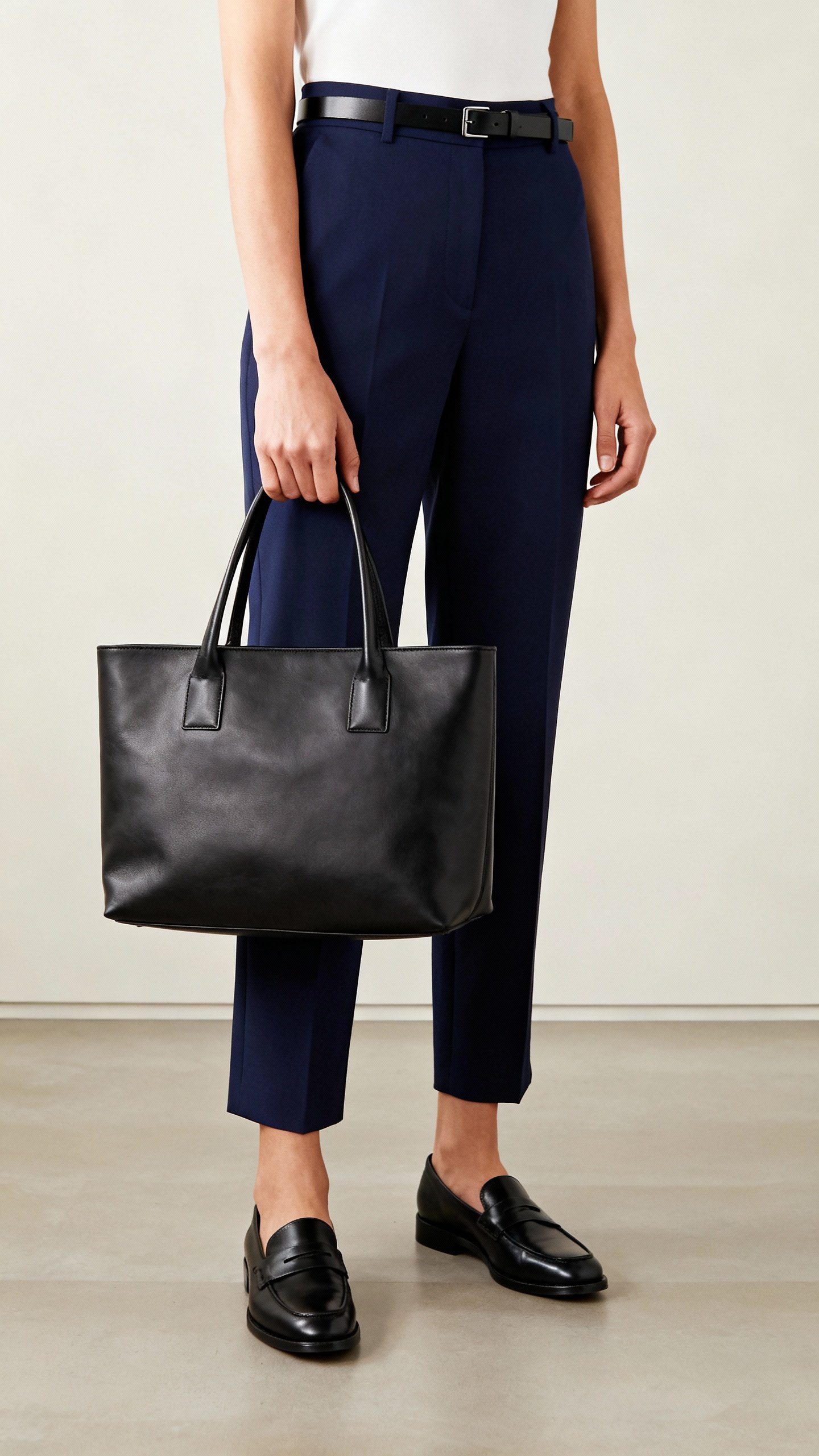 Navy trousers with black loafers and thin black belt, structured tote