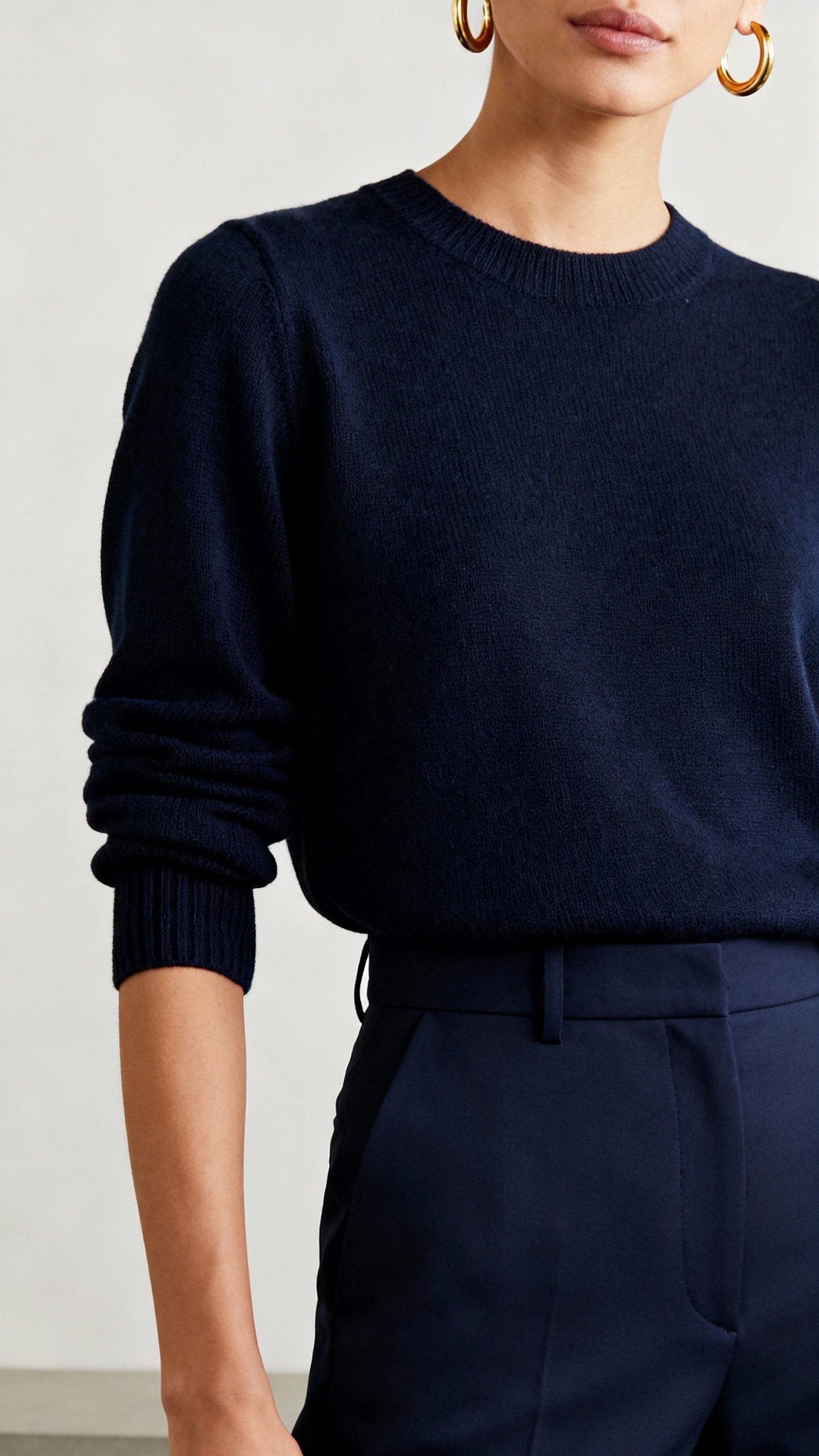 Monochrome navy outfit: tailored trousers, lightweight knit, gold hoop earrings, rolled sleeves clos