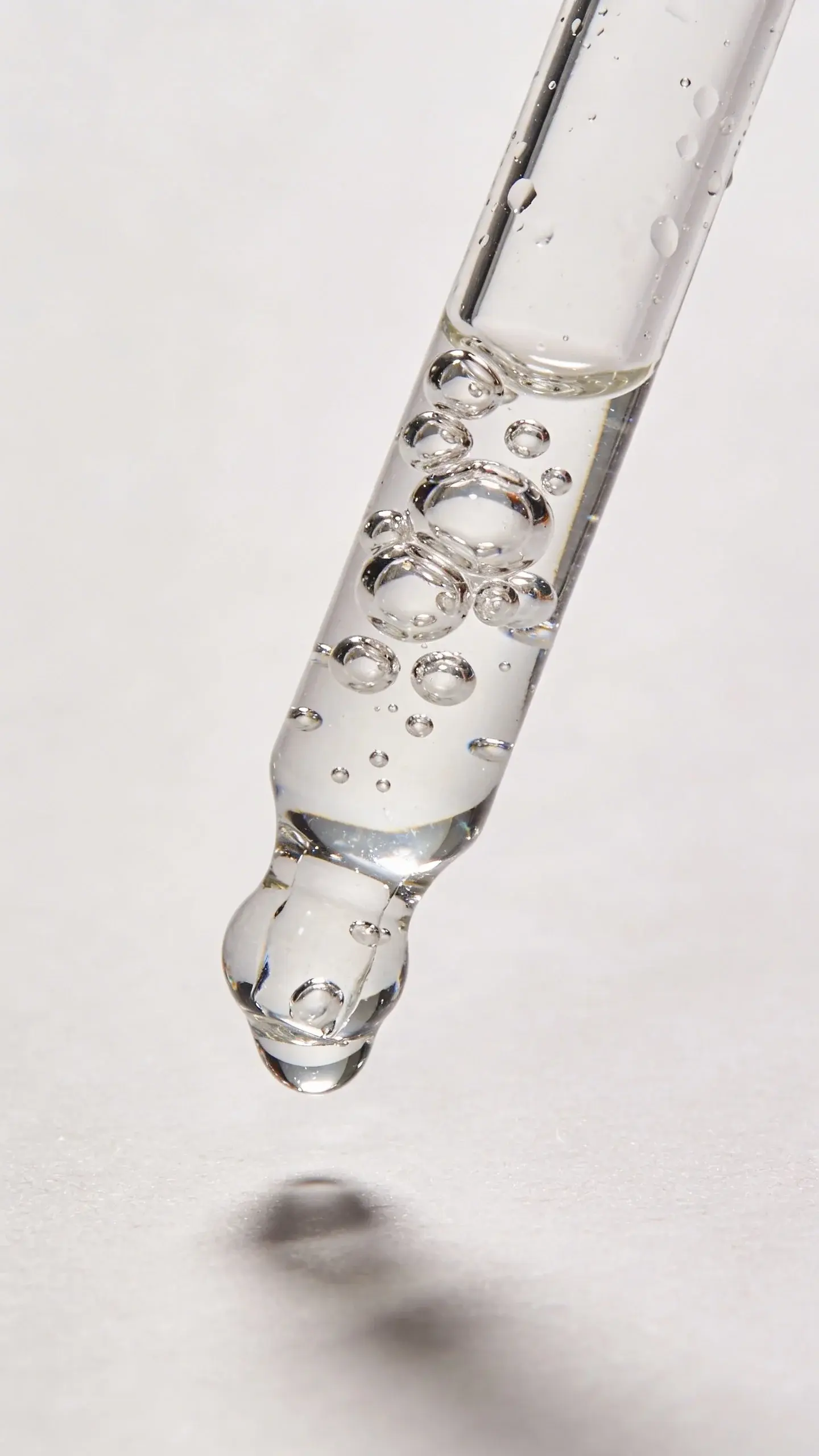 Water beads on glass dropper labeled hyaluronic acid, studio shot