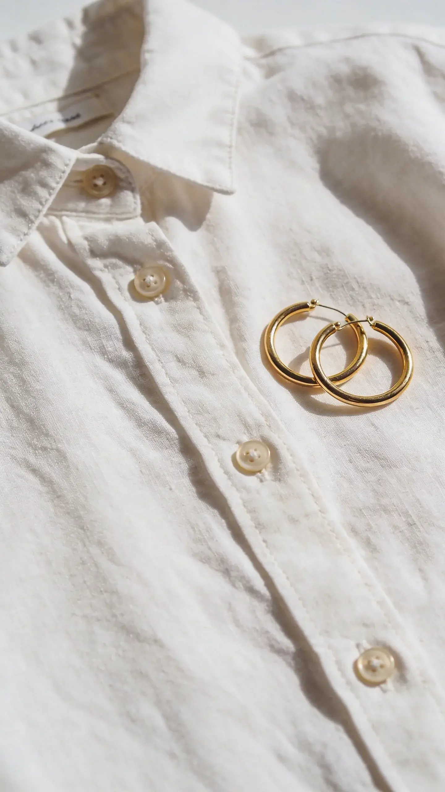 breathable cotton button-down with gold hoop earrings, flat lay