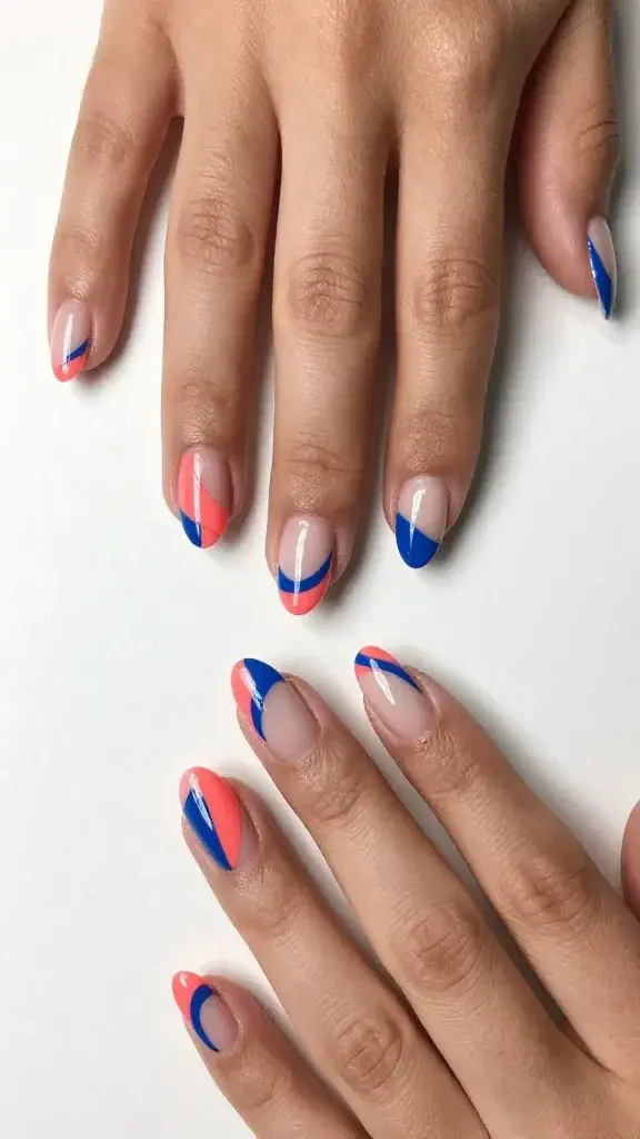 Top-down, high-resolution, realistic photo of two hands resting on a matte white surface, showcasing a negative space geometric manicure on medium-length oval nails. The design uses a limited palette: electric coral and cobalt blue with natural nude nail beds visible. Each nail features crisp, razor-sharp lines created with nail tape: angular color-blocked triangles at the tips, slim cobalt arches curving along one sidewall, and precise cutout half-moon shapes at the base. Index and ring fingers alternate patterns for visual rhythm; thumbs display a bold diagonal split with negative space intersecting coral and cobalt. Edges are ultra-clean and symmetrical with consistent line weight. Finish is a glassy, high-shine top coat that subtly reflects soft window light. Skin tone is warm medium with moisturized cuticles; no jewelry, minimal shadows, modern editorial aesthetic. Camera settings: macro focus, shallow depth of field prioritizing nail surface texture, neutral color balance, true-to-life detail.