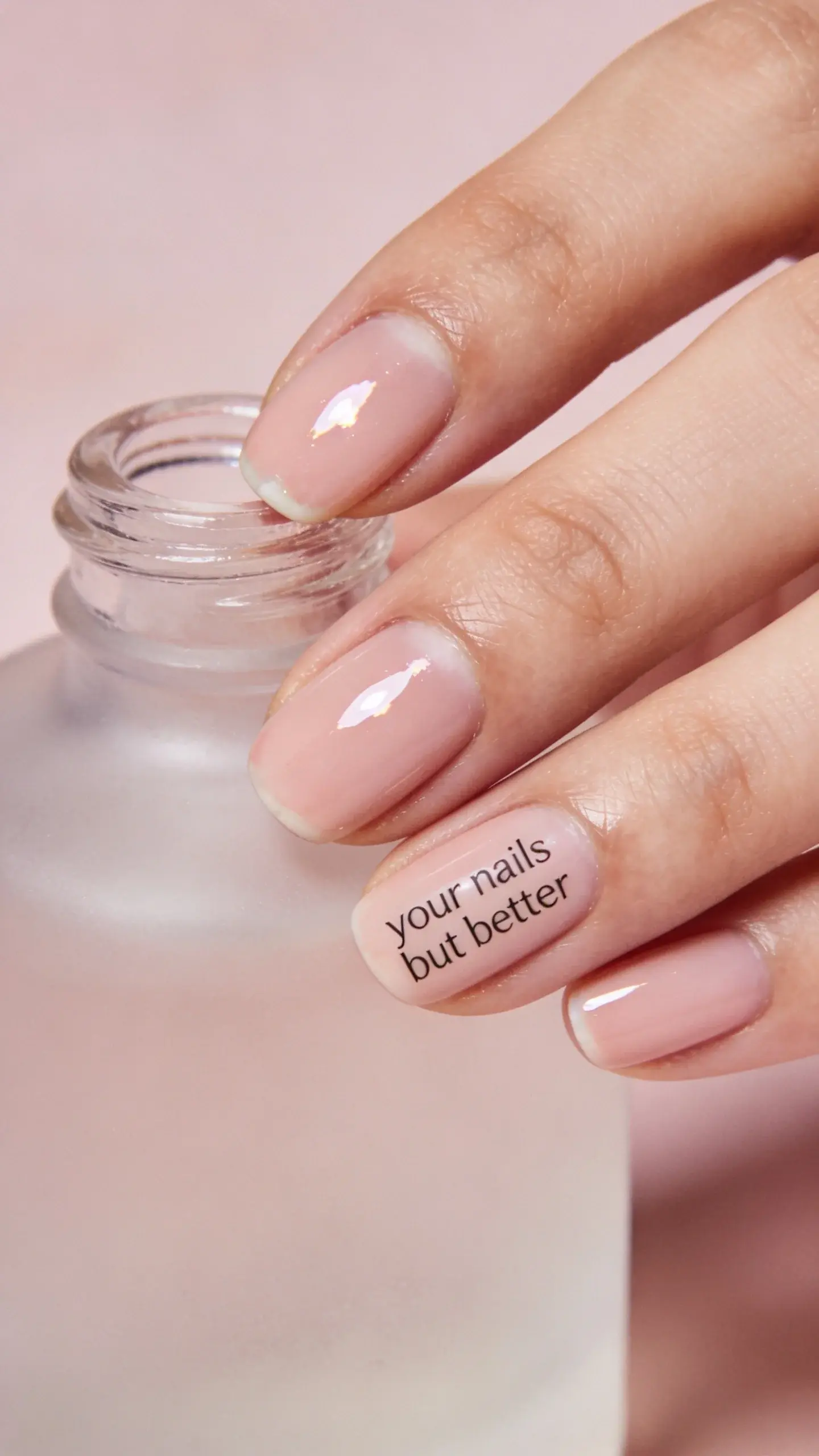 Beauty macro shot: nails in milky pink “your nails but better” finish, cuticles perfectly groomed, slight reflection highlight; hand lightly touching a frosted glass bottle; desaturated, luxury spa vibe; no text.